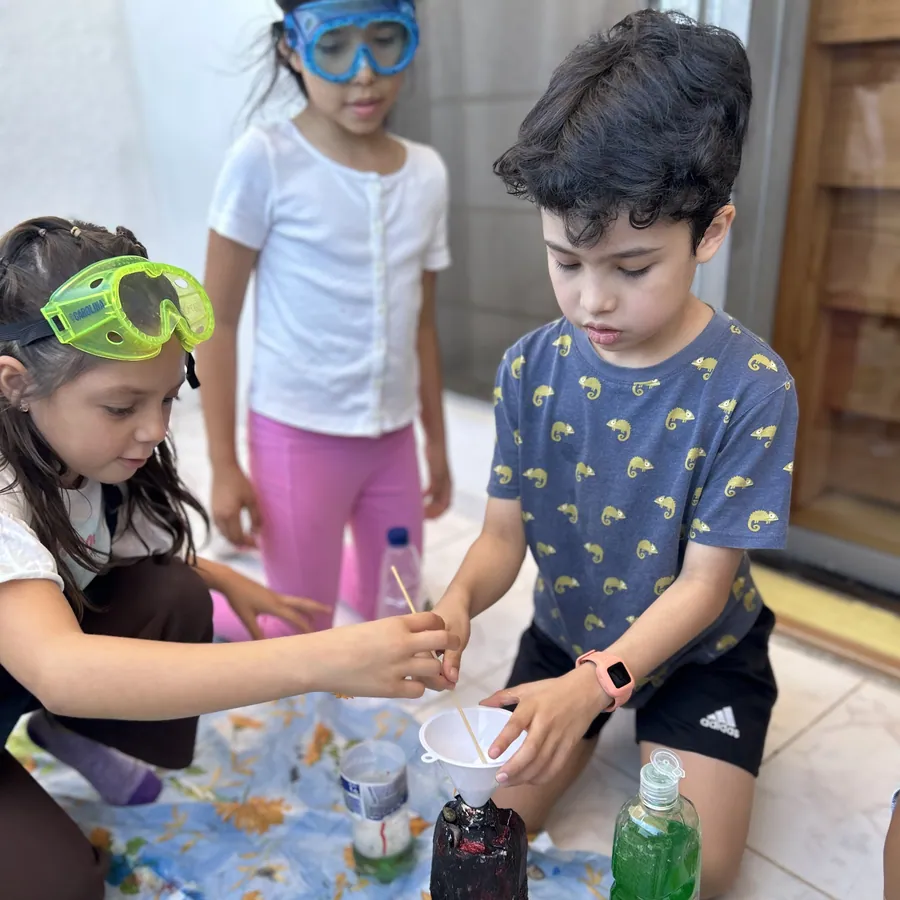 Learners in safety goggles running a science experiment during an afternoon quest at Acton Academy El Salvador