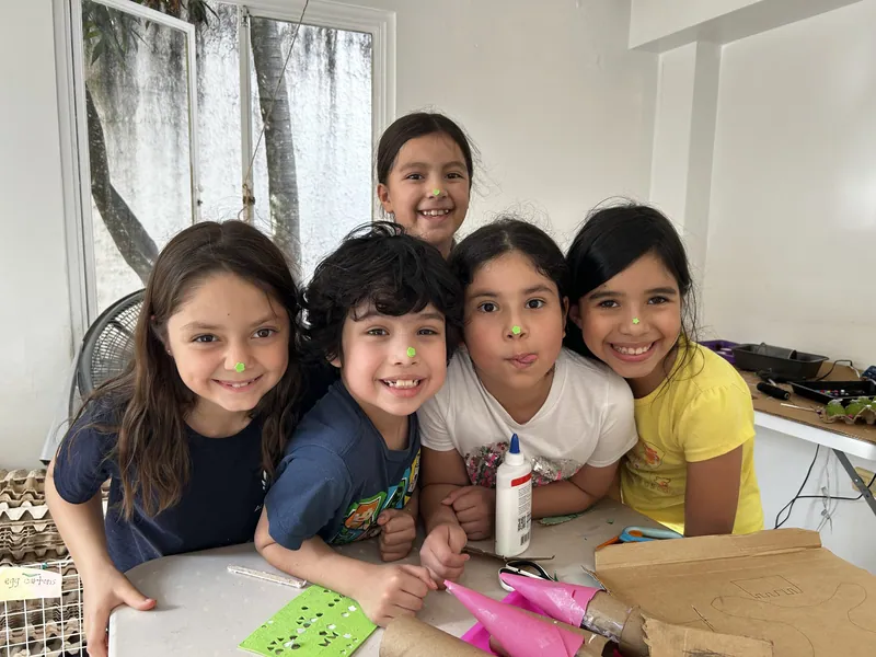 Four learners from Spark Studio laughing together at their work table